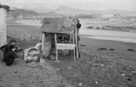 Hombre y niño junto a una chabola destrozada como consecuencia del temporal de viento en las playas de El Bulto y San Andrés. Málaga. Enero de 1963